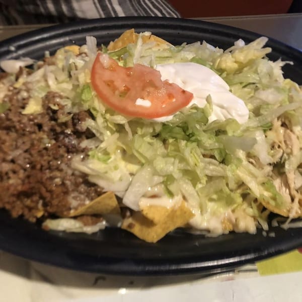 Don Tequila Elyria's nachos with ground beef, shredded lettuce, sour cream, and a tomato slice.