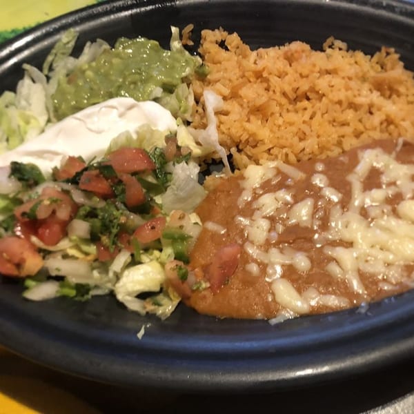 A Mexican dish with rice, refried beans, guacamole, sour cream, and pico de gallo.